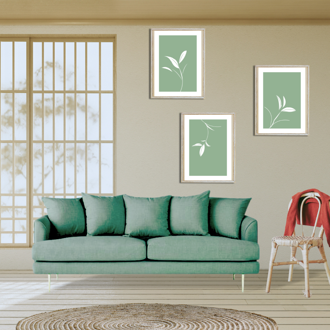 Set of three minimalist white botanical prints on sage green, framed above a green sofa, in a neutral setting.