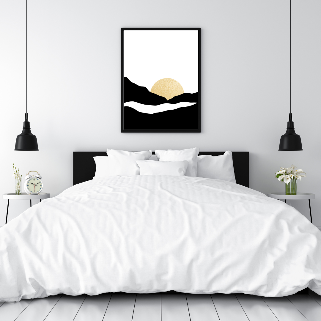 Framed black and gold sunset abstract artwork above a bed with white bedding and black headboard.