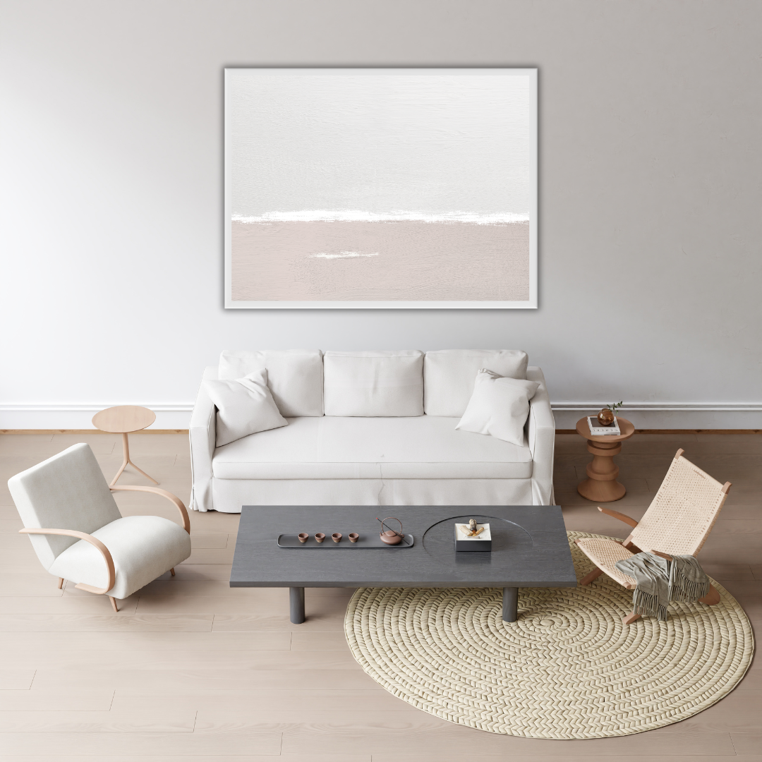 Sea and sky landscape wall art in a minimalist Japandi living room with a white sofa, coffee table, and chairs.