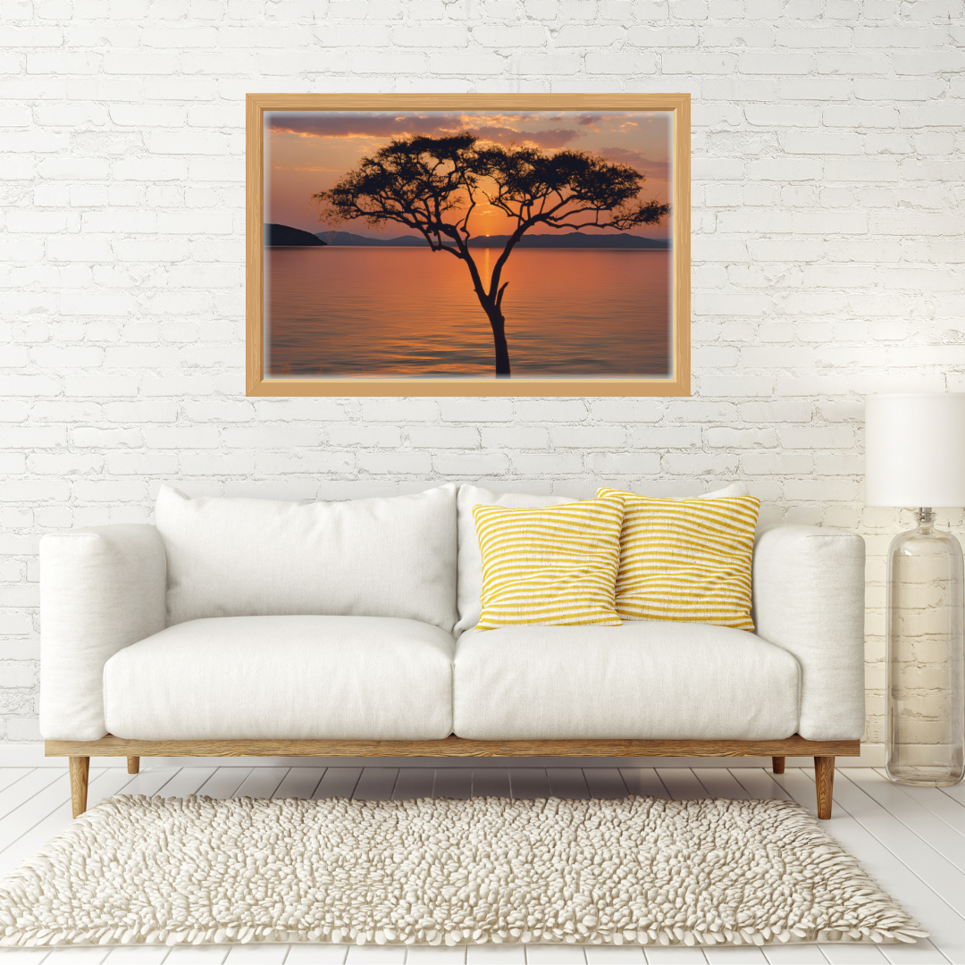 Framed African sunset print with acacia silhouette above a neutral linen sofa in a modern living room.