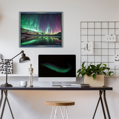 Framed Aurora Borealis print above a minimalist desk with a lamp, a plant, and a computer.