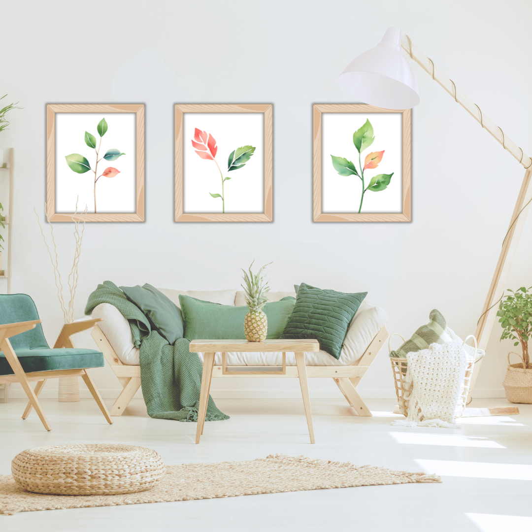 Set of three watercolor leaf prints—green stems with red highlights—framed above a neutral sofa with wooden decor.