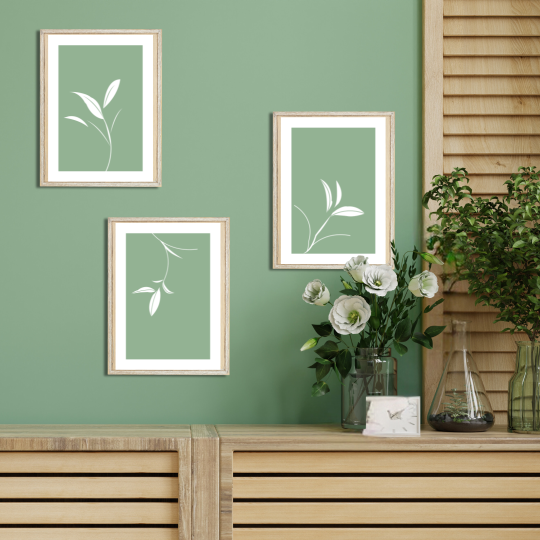 Minimalist gallery wall with white leaf silhouettes on green, styled with houseplants and wood decor.