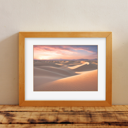 Framed desert sand‑dune print on a wooden shelf with a neutral backdrop.