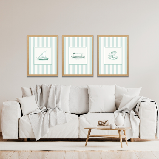 Three framed striped art Dubai coastal art prints of a dhow, an abra, and an oyster above a white sofa in a living room setting.