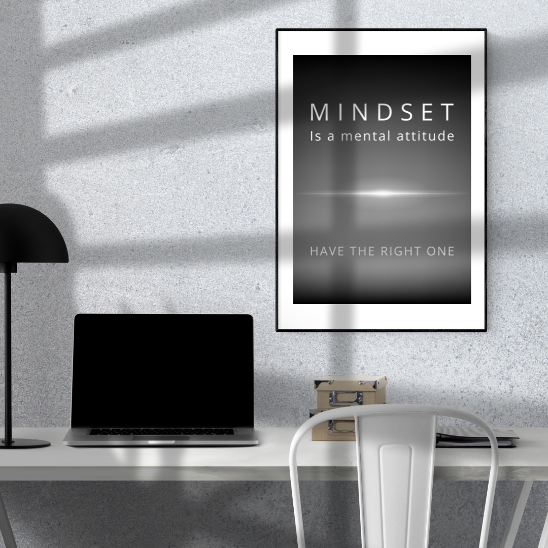 Monochrome quote artwork on the wall above a minimalist home study desk with a laptop and a lamp.