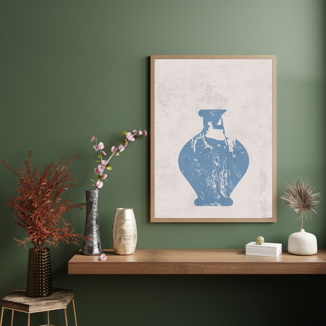Framed artwork of a blue abstract vase on a wooden shelf against a green wall.