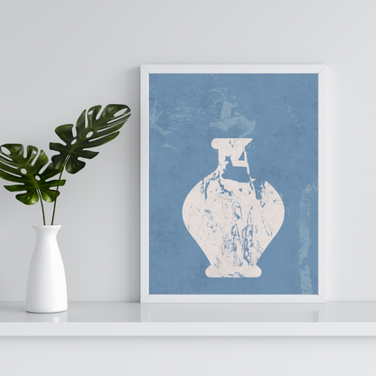 Framed artwork of a neutral abstract vase on a blue background, placed on a white shelf with a plant beside it.