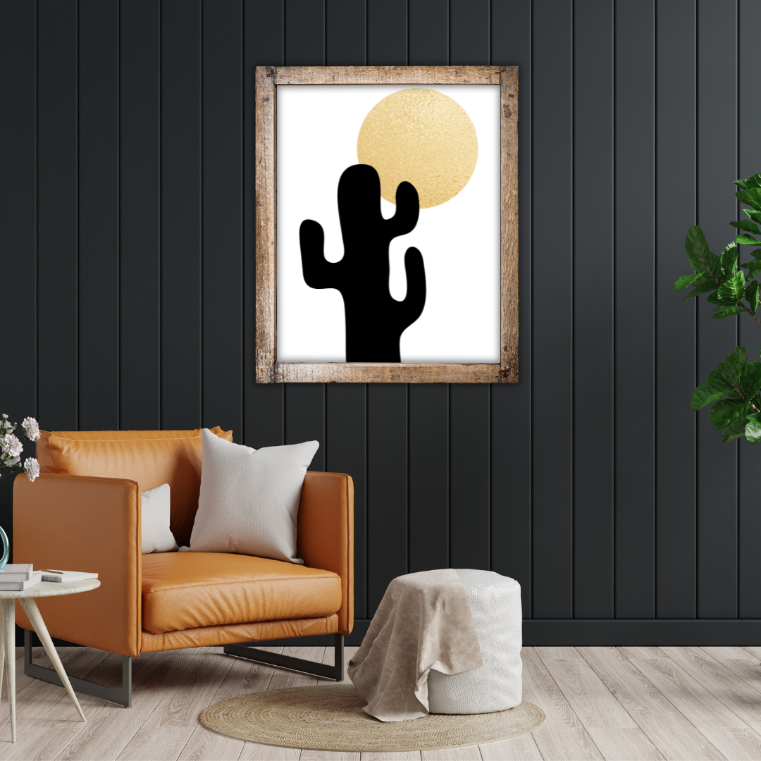 Reading nook with a tan sofa, side table, pouf, and a framed cactus boho style artwork on a black wall.