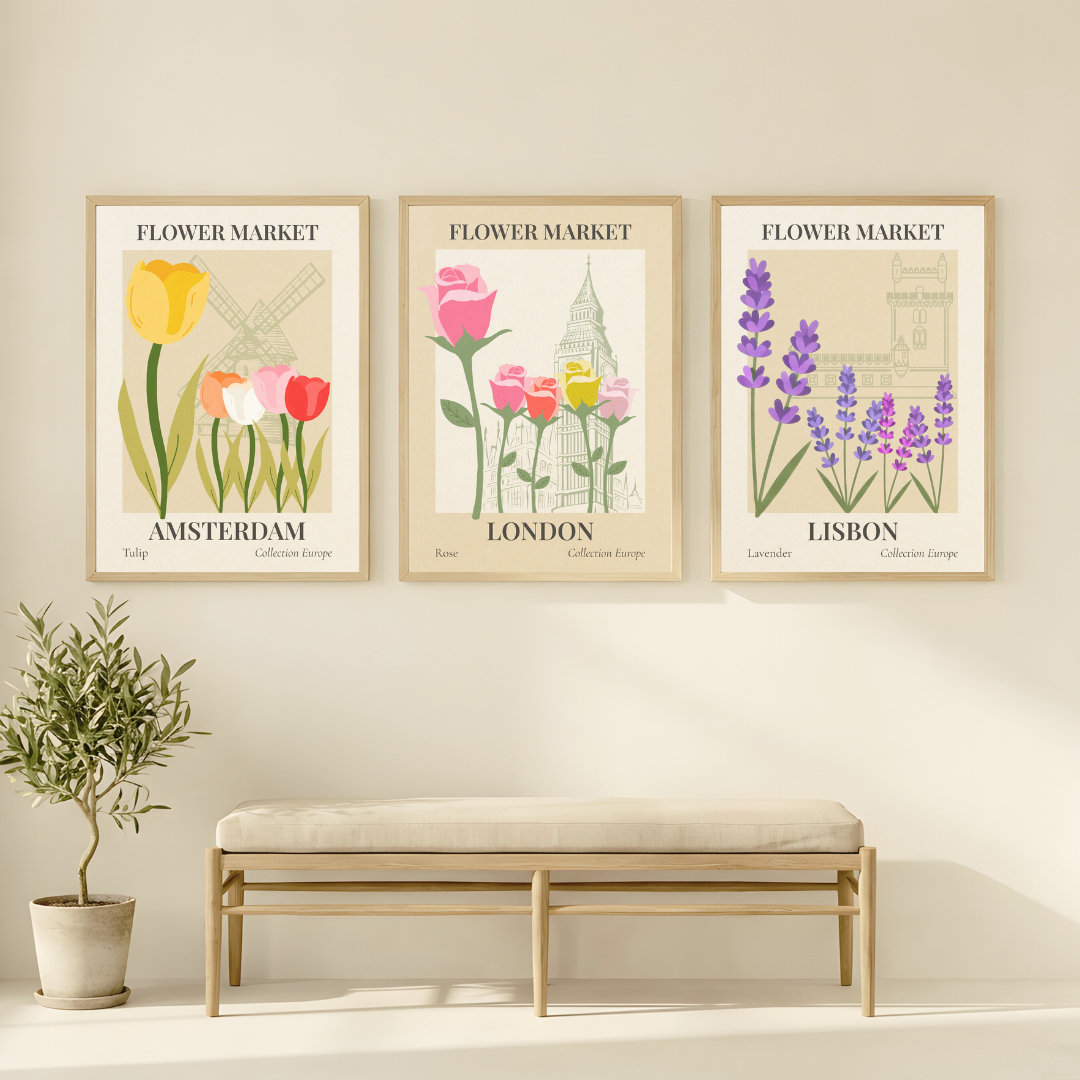 Three framed prints of flowers and city landmarks on a wall with a bench and plant below.