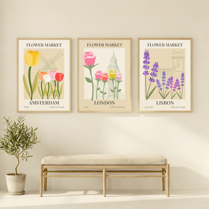 Three framed prints of flowers and city landmarks on a wall with a bench and plant below.