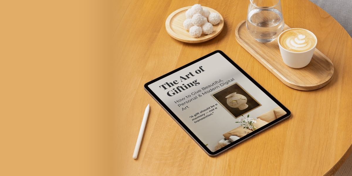 Tablet displaying The Art of Gifting cover on a wooden table with a cup of coffee and a glass of water.