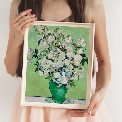 Person holding a framed painting of white flowers in a green vase on a light background