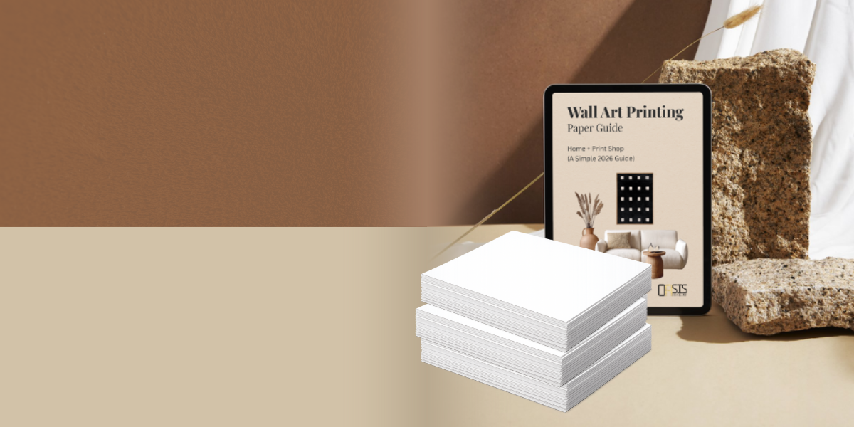 Stack of white paper sheets with a tablet displaying a wall art printing guide on a beige surface.