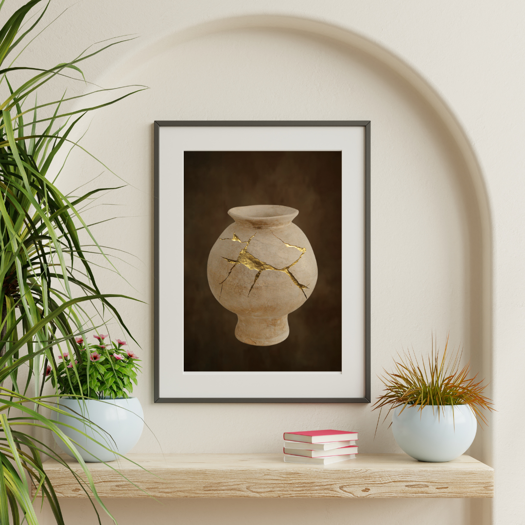 Framed artwork of a cracked vase with gold accents on a wall above a wooden shelf with plants and books.