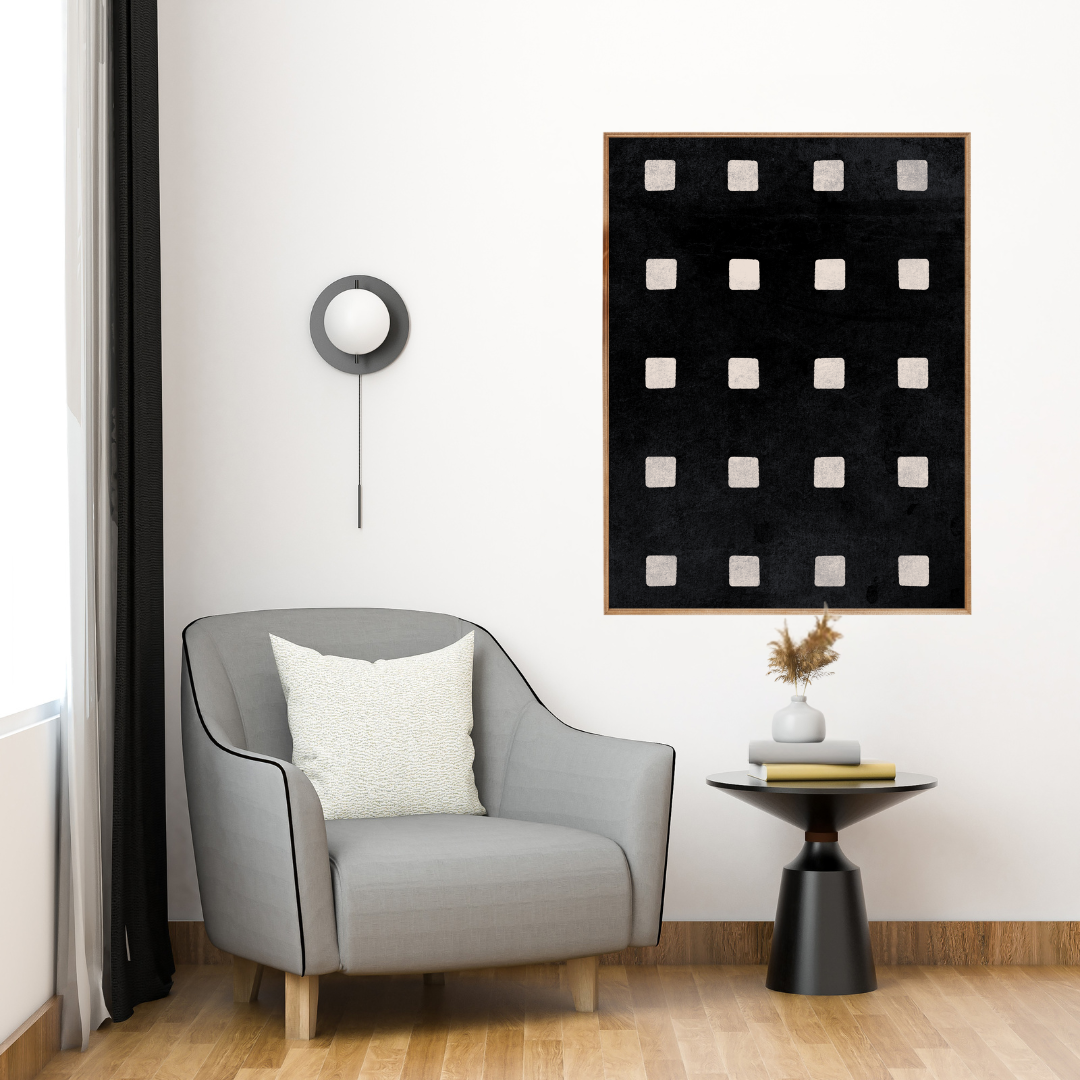 Modern reading nook with a gray armchair, black side table, and an abstract wall art with geometric shapes.