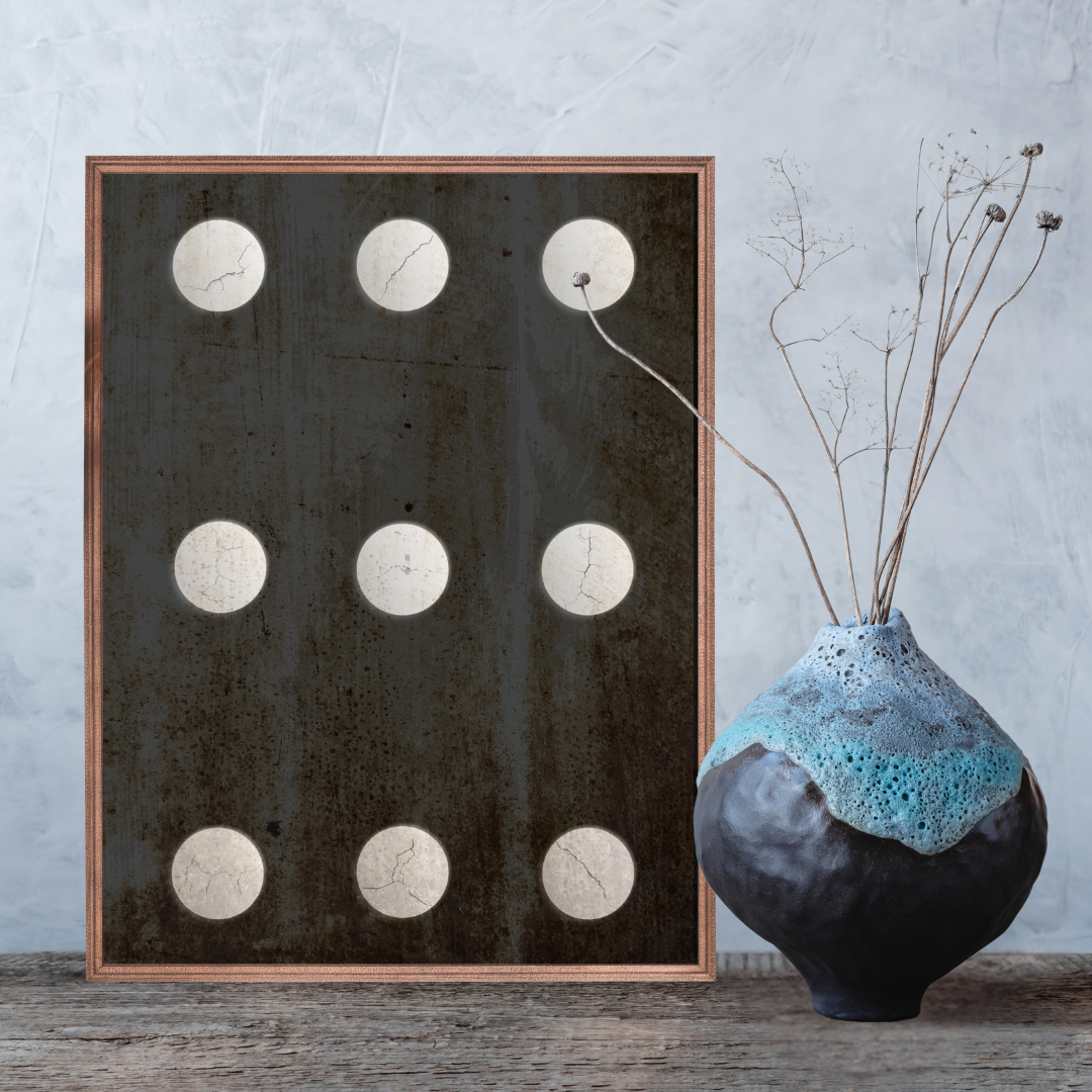 Closeup of a framed Wabi Sabi artwork with circular patterns next to a textured Japandi vase on a wooden surface.